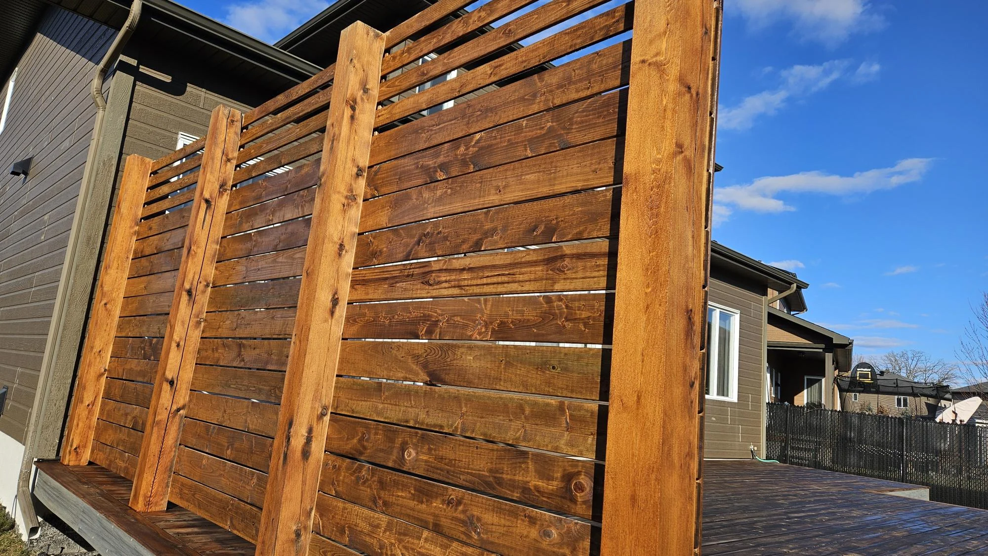 Clôture en bois au fini chaud, sous un ciel bleu.